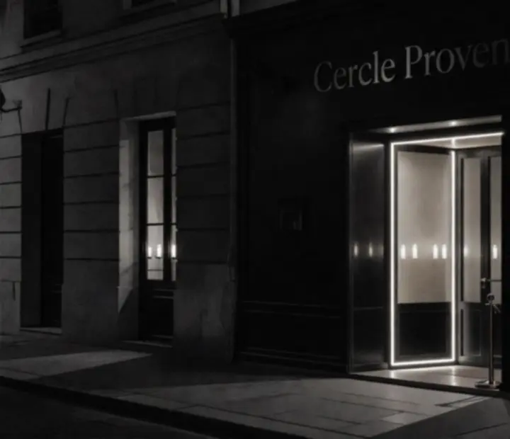 Façade noir et blanc d'un restaurant discret, éclairé par une lumière nocturne.